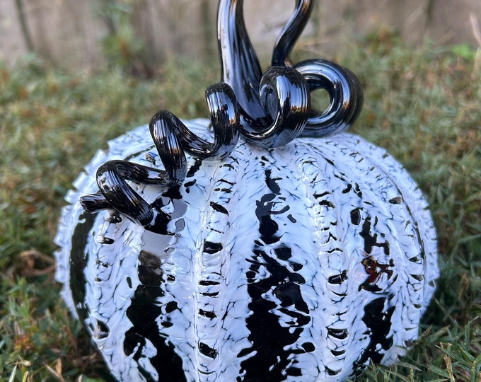 A black and white glass pumpkin with a curled black stem