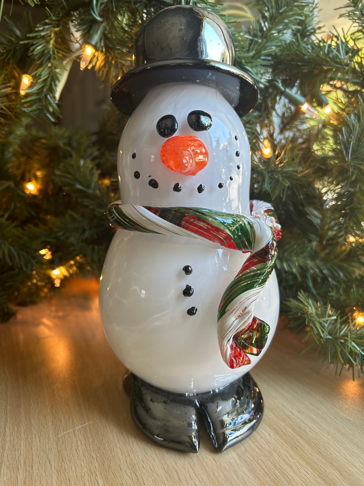 A glass snowman with a black top hat and a red, green, and white scarf